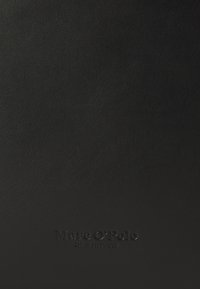 Black leather notebook cover featuring a textured surface and embossed branding, "Marc O’Polo," at the bottom center.