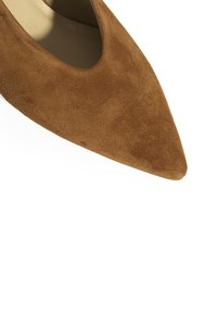 Escarpins en daim marron à bout pointu avec un design échancré ; doublure intérieure lisse et surface texturée présentant un éclat subtil.