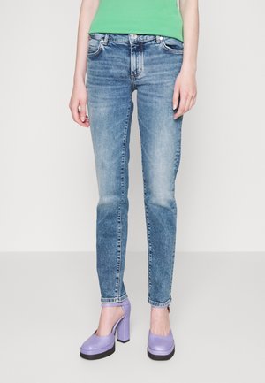Light blue denim jeans with a straight leg design, faded details, and five-pocket style, paired with lavender platform heels.