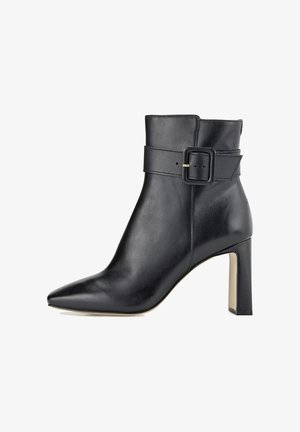 Bottine en cuir noir avec un bout pointu et un talon bloc haut, dotée d'une large sangle avec un détail de boucle carrée. Texture lisse sur toute la surface.