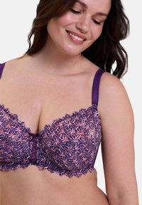 Soutien-gorge en dentelle violette avec motif floral, bords festonnés et couture décorative. Il dispose de bretelles réglables et d'un centre en tulle.