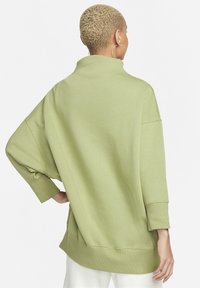 Överdimensionerad grön sweatshirt med hög krage, neddragna axlar och ribbade muddar; har en mjuk textur och rundad fåll.