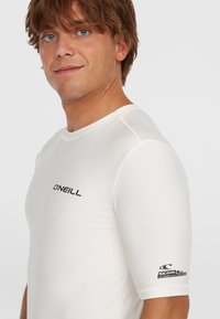 Valge lühikese varrukaga rash guard musta O'Neill logo'ga. Sile tekstuur, UV-kaitse ja kontrastset õmblustäpsust detailides varrukatel.