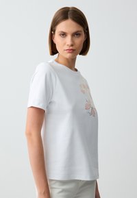 Witte katoenen t-shirt met korte mouwen, voorzien van kleurrijke bloemenmotieven op de voorkant, ronde halslijn en een ontspannen pasvorm.