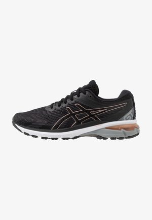 Zapatilla de correr negra y gris con suela blanca, logo en oro rosa, parte superior de malla transpirable y talón acolchado con soporte visible de gel.
