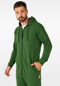 Sudadera con cremallera verde de mezcla de algodón, con bolsillos frontales, capucha ajustable con cordón y detalles de hardware en contraste. Textura suave.