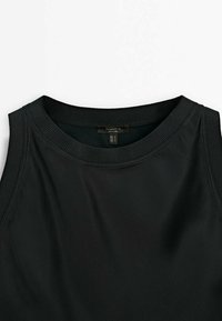 Sort ærmeløs top med rund halsudskæring, lavet af glat stof. Har ribstrikket kant rundt om hals og armhuller. Etiketten er synlig.