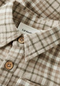 Hnědo-krémová kostkovaná košile s texturovanou tkaninou, dřevěnými knoflíky a špičatým límcem, s visačkou "Lil' Atelier."