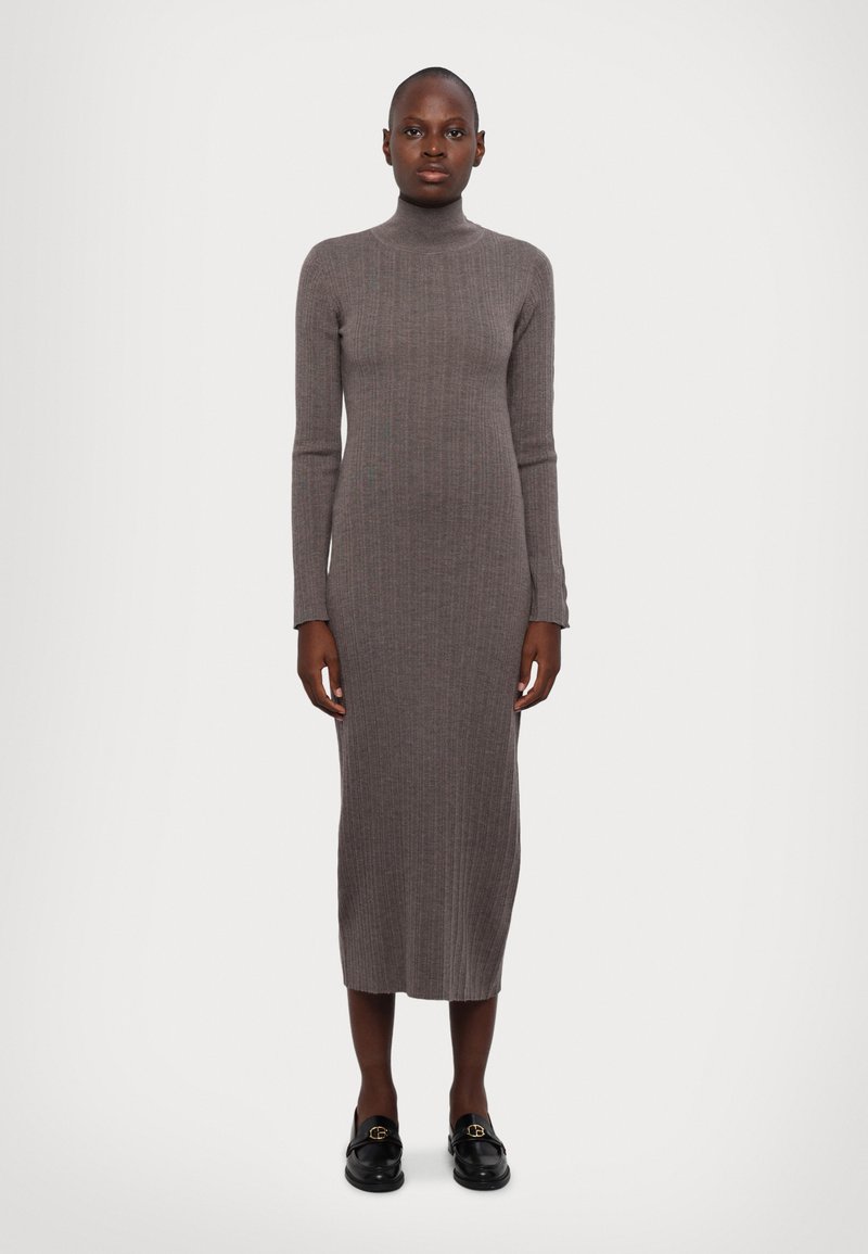 Grå ripet turtleneck kjole med lange ermer, tettsittende form og lengde til midt på leggen. Kombinert med svarte loafers med gull detaljer.