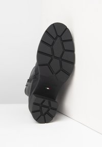 Black boot sole with geometric tread pattern, "NeroGiardini Made in Italy" text, and small Italian flag badge, displayed against white corner.