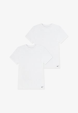 Dwie zwykłe białe koszulki Nike z krótkim rękawem i okrągłym dekoltem, każda z małym czarnym logo Nike swoosh na dolnym lewym brzegu.