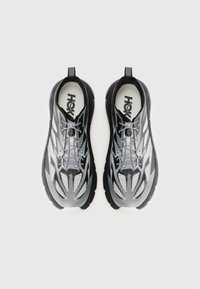 Une paire de chaussures de sport noires et grises avec des tiges à motifs et des languettes de traction, vues de dessus sur un fond blanc.