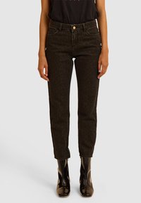 Jeans neri con un sottile motivo leopardato, design aderente, vita media e stile a cinque tasche, abbinati a stivali alla caviglia lucidi.
