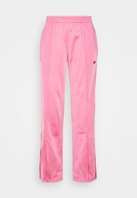 Pink polyester track pants with an elastic waistband, side pockets, and vertical slits at the hem, featuring a small logo on the thigh.