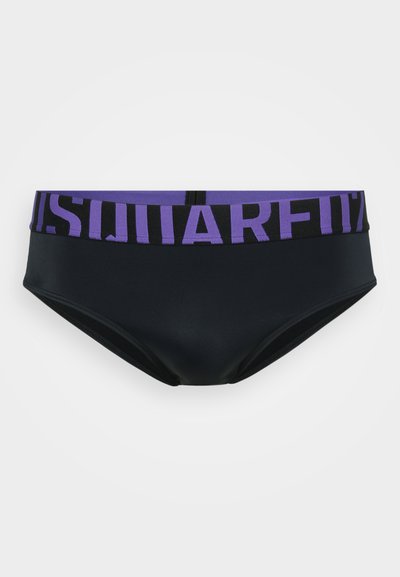 Schwarze Schwimmunterhose mit einem breiten lila Bund, der große schwarze Blockbuchstaben zeigt, präsentiert vor einem schlichten weißen Hintergrund.