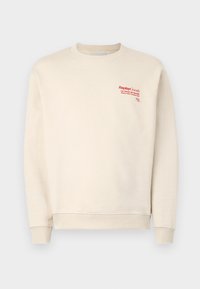 Cream sweatshirt made of soft fabric, featuring ribbed cuffs and hem. Red logo text on the upper left side, smooth texture overall.