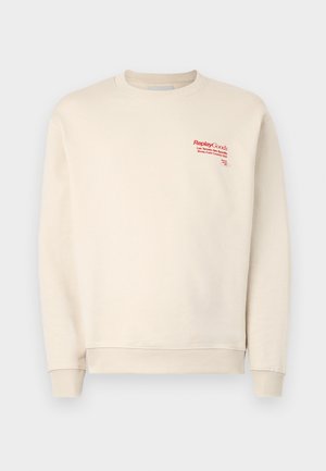 Cream sweatshirt made of soft fabric, featuring ribbed cuffs and hem. Red logo text on the upper left side, smooth texture overall.