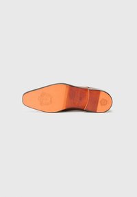 Suela de zapato de cuero con cuero naranja liso, con logo y detalles grabados, forma curva y borde oscuro contrastante.