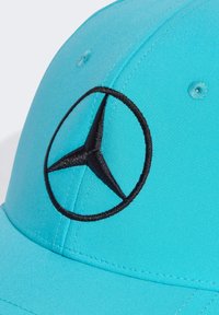 Turkis baseballcap med sort broderet Mercedes-logo. Har en buet skygge og tekstureret stof. Fire ventilationsøjer inkluderet.