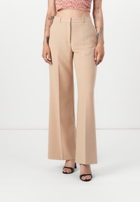 Beige wide-leg trousers with a smooth texture, featuring a tailored high waist, front pleats, and discreet side pockets.