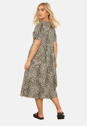 Beige en zwarte luipaardprint midi-jurk, korte mouwen, relaxte pasvorm, gelaagde rok, lichtgewicht stof, gedragen met donkere instappers.