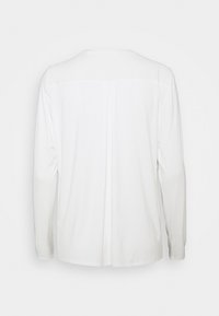 Biała koszula z długim rękawem i okrągłym dekoltem, z delikatnym plisowaniem z tyłu oraz miękką, gładką teksturą materiału. Bez widocznych wzorów ani akcentów.