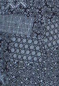 Námorní tkanina s mnoha složitými vzory: květinové motivy, geometrické tvary a víry v kontrastní světle modré barvě. Texturový povrch.