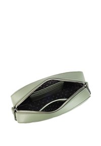 Zelená kožená taška se zipovým uzavřením. Interiér je černý s bílými puntíky, obsahuje přihrádky na karty a centrální přihrádku.