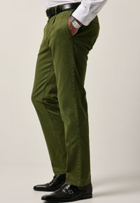 Groene katoenen broek met een slim fit, voorzien van zijzakken en een nette afwerking. Gecombineerd met zwarte leren schoenen en een horloge om de pols.