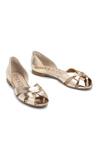 Metaliczne złote płaskie buty z odkrytą palcą, z plecionym paskiem i płaską podeszwą. Gładka tekstura z błyszczącym wykończeniem. Logo widoczne na wkładce.