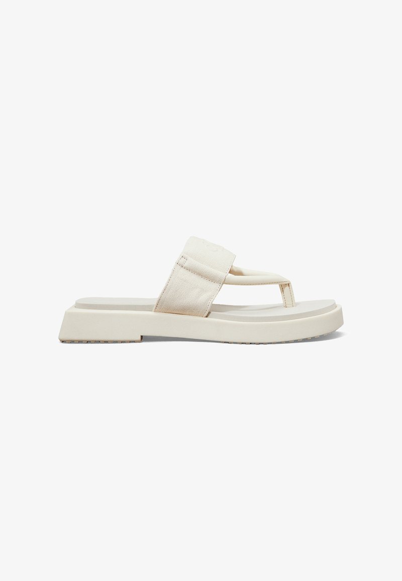 Lys beige flip-flop sandal med en tyk gummisål, stofrem og minimalistisk design. Har en dekorativ tæerem og tekstureret sål.