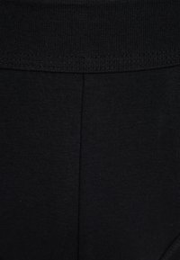 Sorte leggings med en tekstureret, elastisk talje. Glat, strækbart stof uden synlige mønstre eller hardware-detaljer.