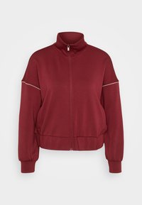 Bordeaux zip-up jakke med høy krage, elastiske mansjetter og liv. Har en smal hvit stripe over skuldrene. Myk stofftekstur.
