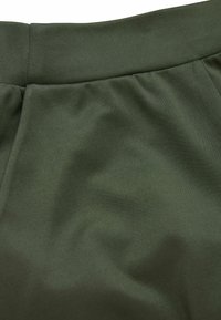 Olivgrüner Stoff mit strukturierter Oberfläche, ausgestattet mit einem glatten Bund und gerafften Details, typisch für das Design von Freizeitpants.
