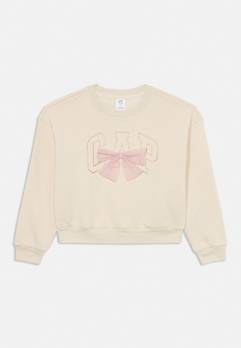 Bež majica s kapuljačom s skrajšanim dizajnom, ki ima vezeni logotip "GAP" in roza prosojno pentljo na sredini. Mehka, teksturirana tkanina.