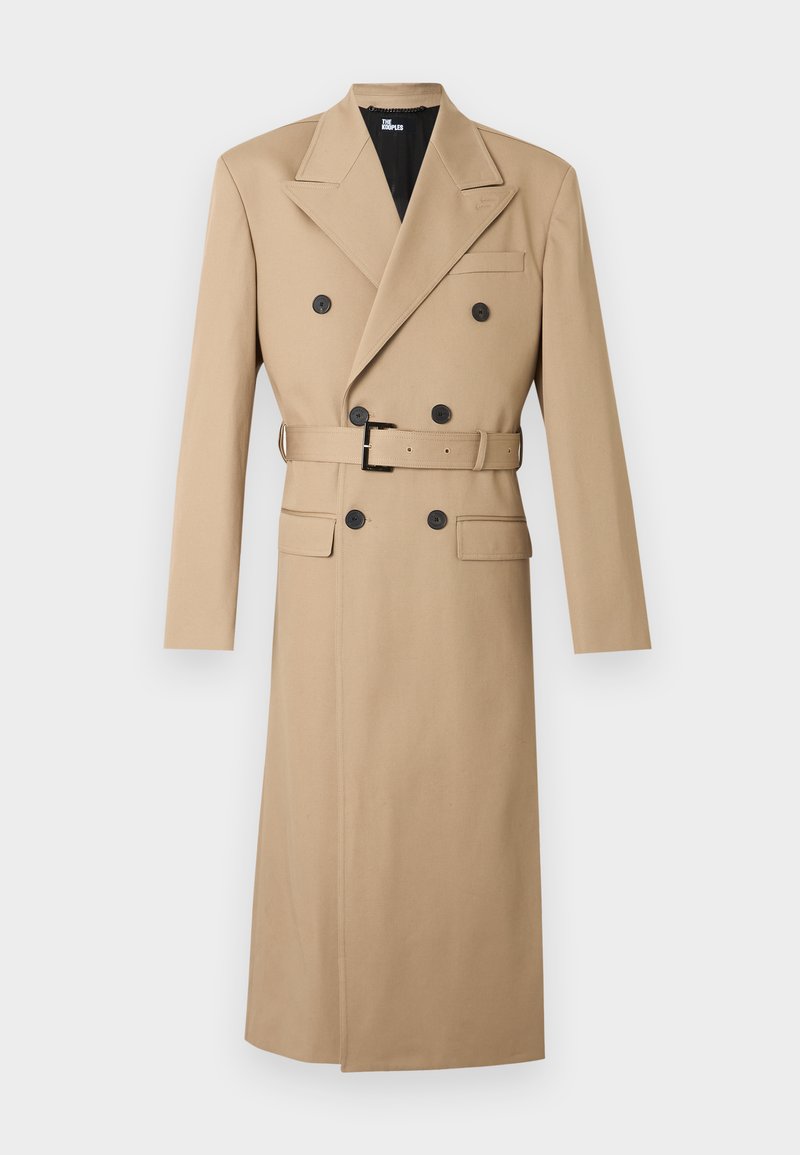 Trench-coat beige avec un devant croisé, de grands boutons noirs, de larges revers et une ceinture assortie à la taille. Longueur mi-mollet.