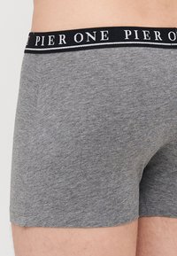 Graue Baumwoll-Boxershorts mit einem schwarzen Bund, auf dem der Schriftzug "PIER ONE" in Weiß prangt. Der Stoff hat ein weiches, leicht strukturiertes Aussehen.