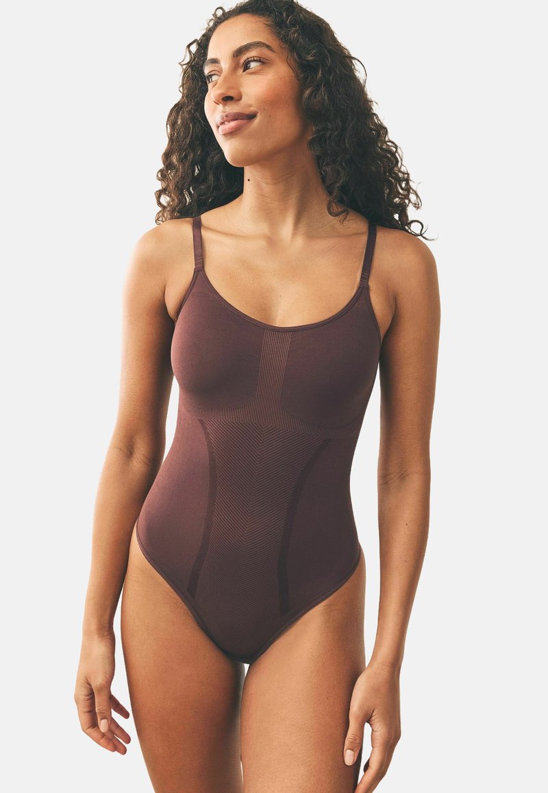 Bordo bodysuit s podesivim naramenicama, bešavnom dizajnom, teksturiranim panelima i prilagođenim oblikom koji naglašava struk i grudni koš.