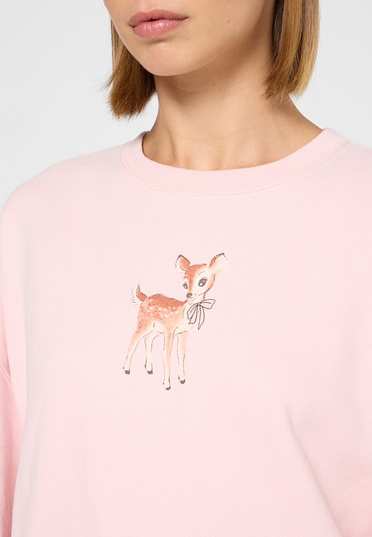 Leuchtend rosa Sweatshirt mit rundem Ausschnitt, das ein im Aquarellstil gedrucktes Reh mit einer Schleife auf der Vorderseite zeigt. Weicher Stoff.