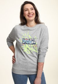 Šedá mikina s potiskem ve stylu graffiti, znázorňující dodávku a neonově zelené akcenty. Má dlouhé rukávy a kulatý výstřih. Hladká textura.