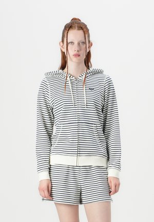 Striped zip-up hoodie in navy and white with a drawstring hood, front pockets, and ribbed cuffs. Paired with matching shorts.