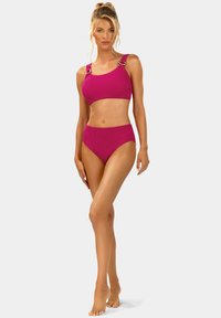 Fuksjowy bikini z prążkowanego materiału, w skład którego wchodzi krótka bluzka z metalicznymi akcentami oraz wysokim stanem, prezentujący strukturalny materiał.