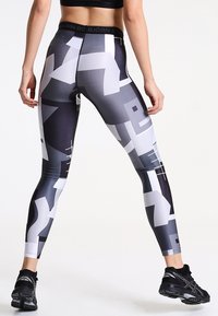 Leggings a vita alta con un motivo geometrico in bianco, nero e grigio, realizzati in un tessuto elasticizzato e con cuciture a contrasto lungo le cuciture.