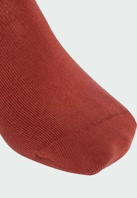 Red cotton sock featuring a smooth, ribbed texture, a rounded toe, and a seamless design for comfort.