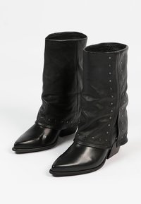 Bottines noires en cuir avec un design décontracté, des pointes effilées et des clous argentés le long des coutures latérales. Talons bas empilés.