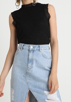 Haut noir sans manches avec bordure en dentelle associé à une jupe en denim bleu clair délavé taille haute avec une fente sur le devant.