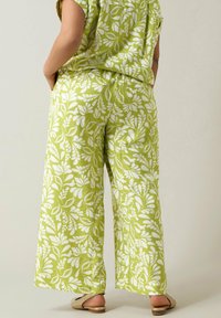 Groene lichtgewicht broek met een wit botanisch patroon, voorzien van een ontspannen pasvorm, zijzakken en een gladde stoftextuur.