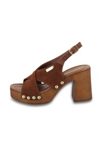 Sandal en suède marron à plateforme avec des bandes croisées, des clous dorés sur le devant et un talon en bois marron épais. Sangle réglable avec boucle.