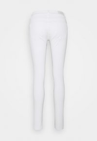 Jeans de mezclilla blanca con un corte ajustado, que cuentan con dos bolsillos traseros y una cintura de altura media, presentando una textura suave y un diseño limpio.