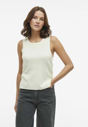 Top senza maniche di un leggero color beige chiaro con scollatura rotonda, texture a coste e vestibilità rilassata, abbinato a jeans neri a vita alta.